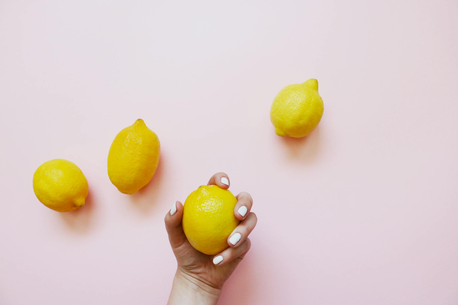 Hands holding lemons on a soft pink background, symbolizing fresh beginnings and natural intimacy